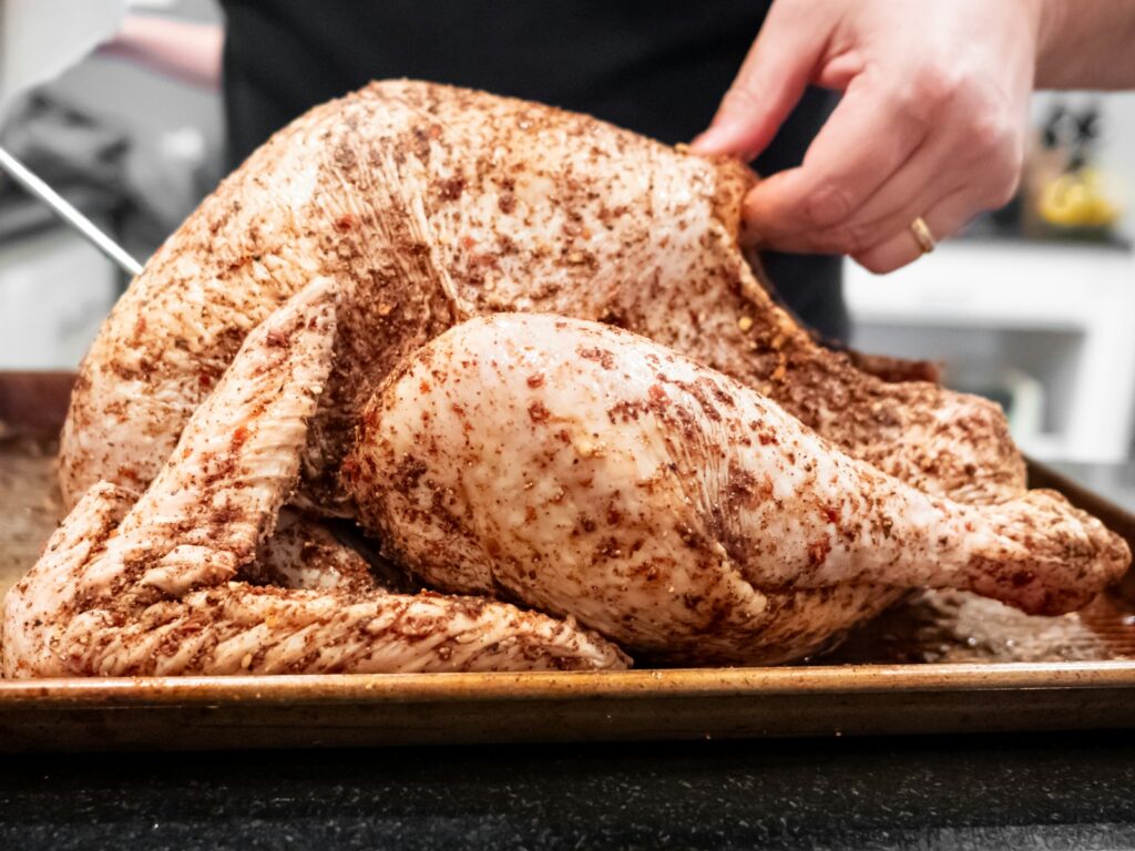 A person slicing a turkey on a tray