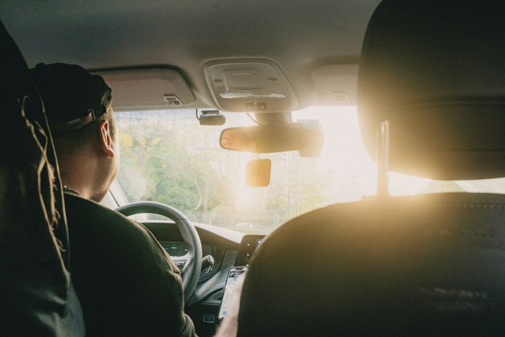 a man driving a car with the sun shining through the windshield