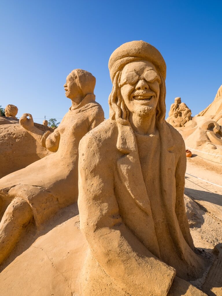 a sand sculpture of a man sitting in the sand